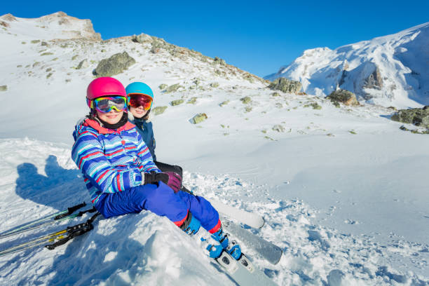 istock Two happy girls in ski mask sit over mountain view 1250045219