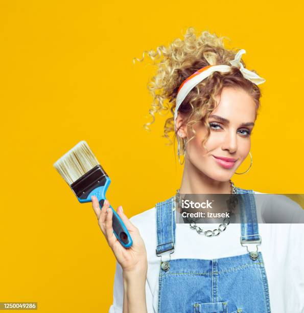 Young Woman In Coveralls Holding Paintbrush Stock Photo - Download Image Now - DIY, Women, Studio Shot