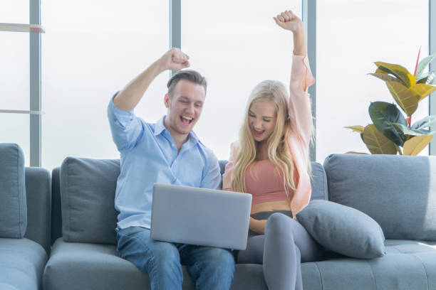 istock Smiling business blonde, white couple relaxing, using computer laptop to work from home and talking on sofa, spend time together in quarantine in corona virus concept. 1250050835