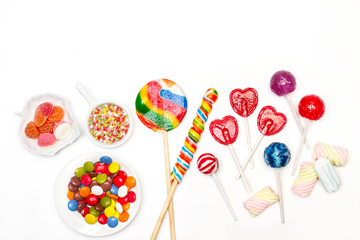Assorted candies and lollipos on a white background in a top view