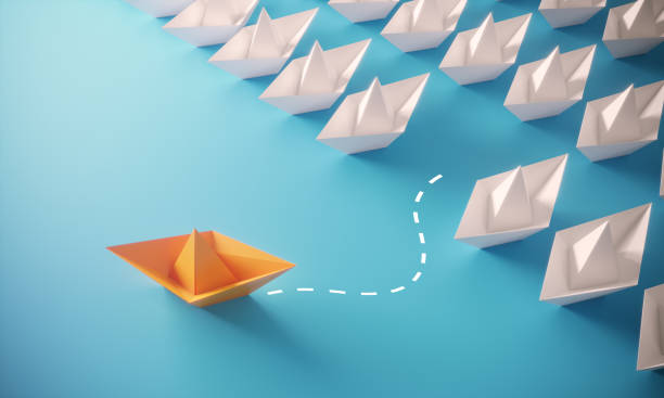Leadership Concept With Paper Boats White paper boats and orange colored one standing out from the crowd, can be used leadership/individuality concepts.( 3d render ) toy boat stock pictures, royalty-free photos & images