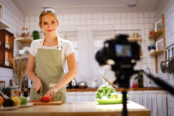linda jovem blogueira ao vivo cozinhando na cozinha para trabalhar em casa. covid-19 - women home video camera camera vitality - fotografias e filmes do acervo