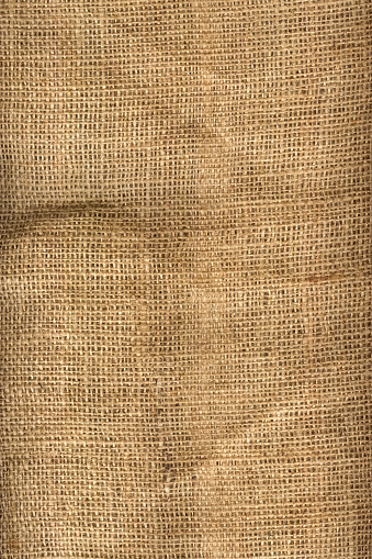 A detailed shot of a rough burlap fabric. Thread and fiber fabric close-up. Full frame. Multitask background. View from above.