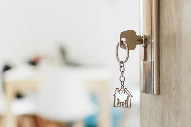 Key with keychain in a house shape and family in the door keyhole. Buy new home concept. Opened door to a new house. Key with keychain in a house shape and family in the door keyhole. Buy new home concept. Real estate market. property security stock pictures, royalty-free photos & images