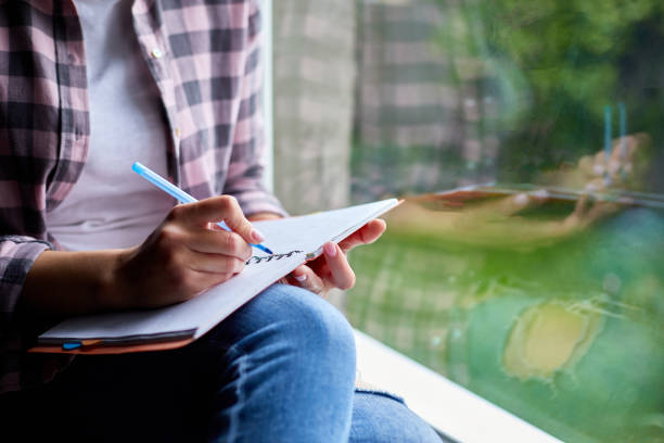 istock Woman, sitting at window at home, writes in notebook goals 1250064283