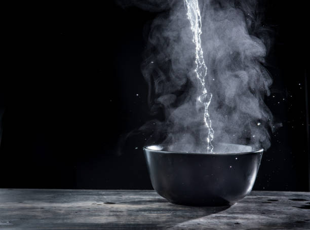 Pouring hot water into into a bowl on a black background