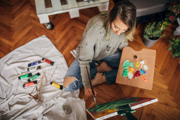 hermosa artista femenina pintura en el suelo en casa - oil painting painted image art studio fun fotografías e imágenes de stock