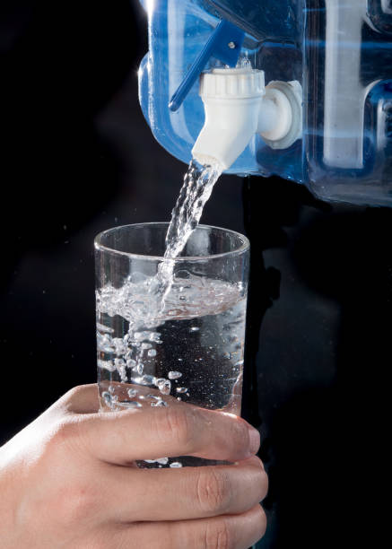 istock Glass filled with drinking water from faucet plastic water container on a black background 1250065738