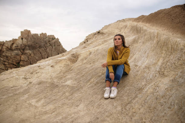 istock Young woman sitting on rocks 1250065779