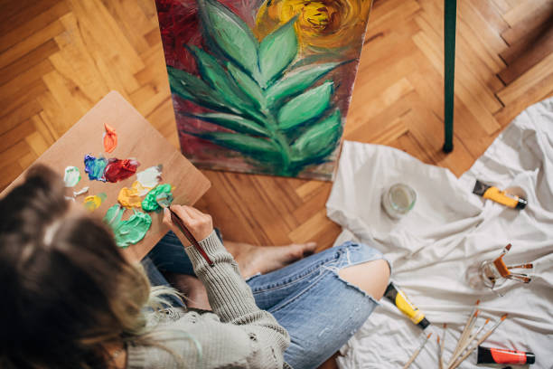 hermosa artista femenina pintura en el suelo en casa - oil painting painted image art studio fun fotografías e imágenes de stock