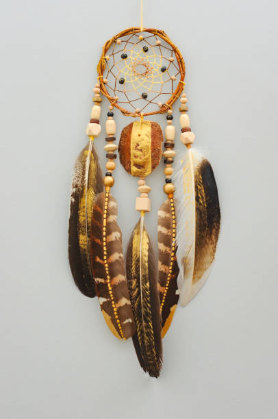 istock Native dream catcher with painted golden feathers on gray background 1250066035