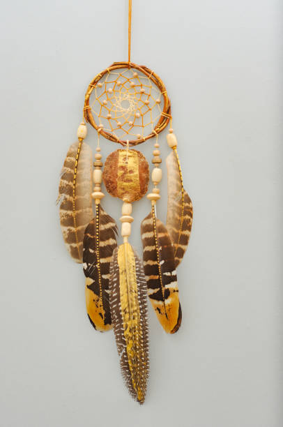 istock Native dream catcher with painted golden feathers on gray background 1250066050