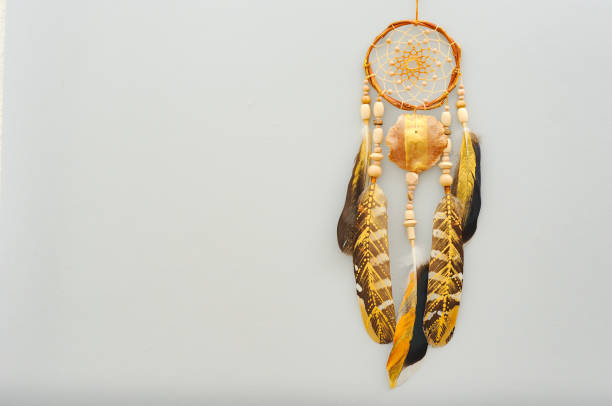 istock Native dream catcher with painted golden feathers on gray background 1250066066