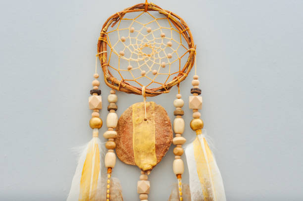 istock Native dream catcher with painted golden feathers on gray background 1250066072