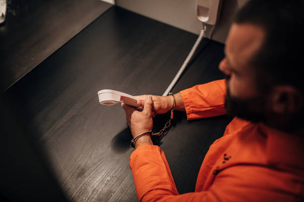 istock Young prisoner in orange jumpsuit sitting in prison visiting room 1250069813