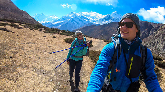 Couple trekking in the Manang Valley, Annapurna Circus Trek, Himalayas, Nepal, with the view on Annapurna Chain and Gangapurna. Dry and desolated landscape.  High snow capped mountain peaks. Happiness
