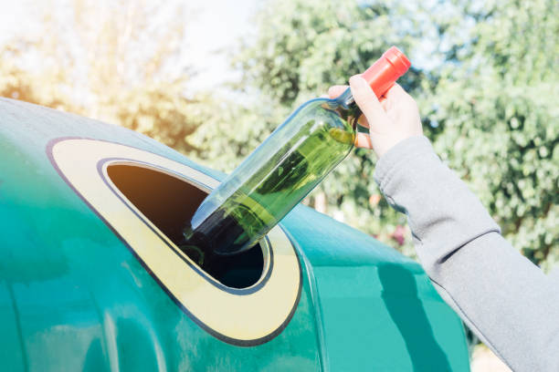 istock Hand throwing glass bottle in recycling bin 1250072994