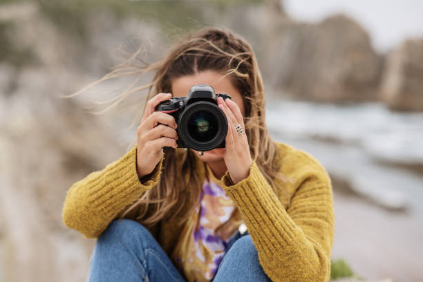 istock Young woman using a DSLR camera in a beautiful coast area 1250072995