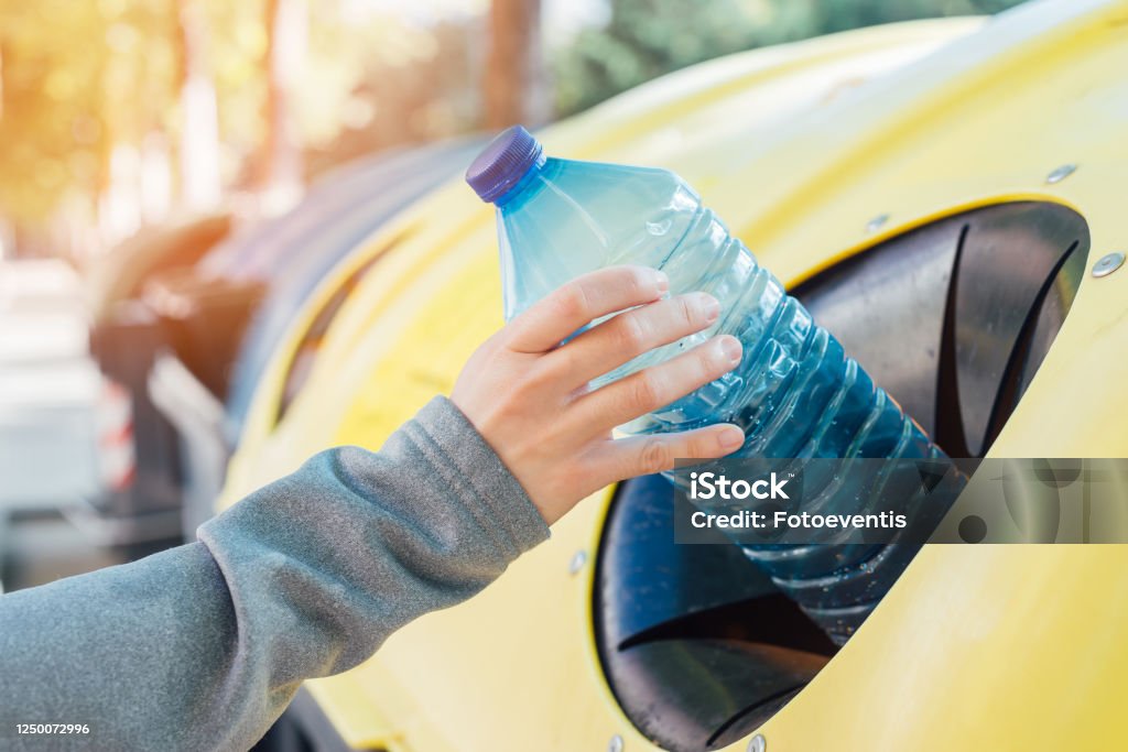 Close up hand throwing empty plastic bottle into the trash Recycling Stock Photo