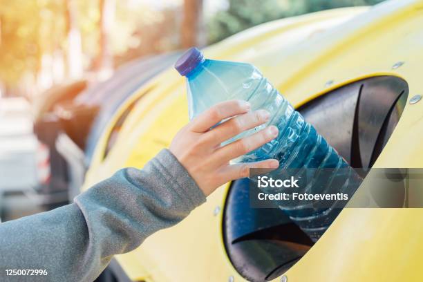 Close Up Hand Throwing Empty Plastic Bottle Into The Trash Stock Photo - Download Image Now
