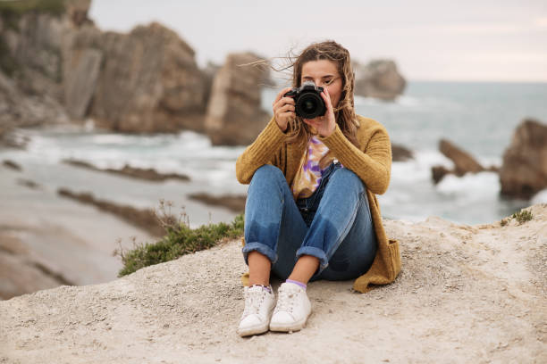 istock Young woman using a DSLR camera in a beautiful coast area 1250073780