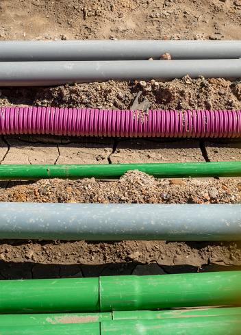 A variety of plastic pipes in a large trench on a construction site, building work.
