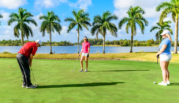 trio joue au golf sur un beau vert scénique, homme et deux femmes sportives - golf golf swing putting cheerful photos et images de collection