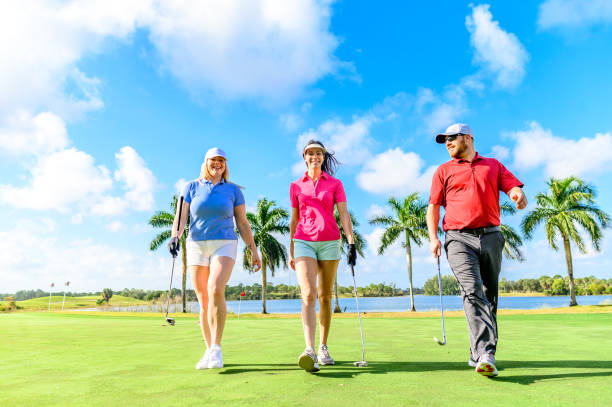 trio joue au golf sur un beau vert scénique, homme et deux femmes sportives - golf golf swing putting cheerful photos et images de collection