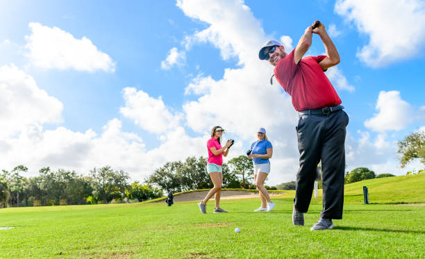 trio joue au golf sur un beau vert scénique, homme et deux femmes sportives - golf golf swing putting cheerful photos et images de collection