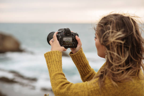 istock Young woman using a DSLR camera in a beautiful coast area 1250080001