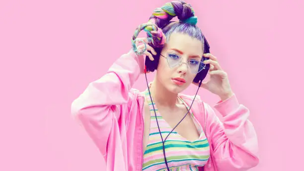 Photo of Portrait of young woman with headphones against pink background