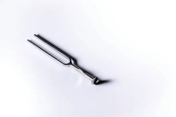 An isolated metallic tuning fork in a white background with space for text
