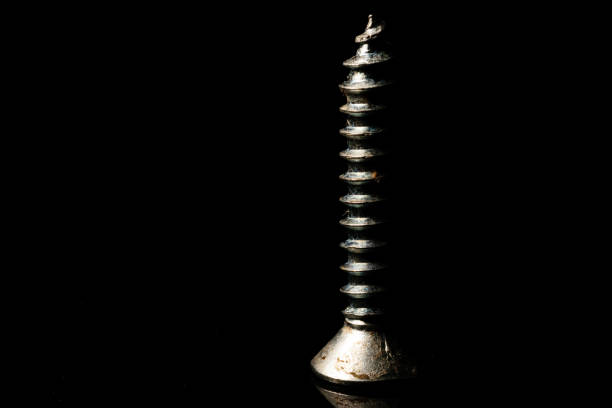 istock An isolated screw placed on a reflective surface with a dark background 1250081351