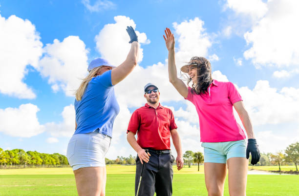 trio joue au golf sur un beau vert scénique, homme et deux femmes sportives, femmes high five - golf golf swing putting cheerful photos et images de collection