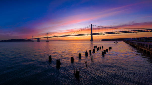 san francisco-oakland bay bridge bei sonnenaufgang mit bunten wolken - san francisco county embarcadero center bay bridge built structure stock-fotos und bilder