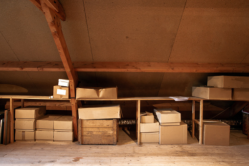 Old wooden attic interior with old cardboard boxes for storage or moving, close-up