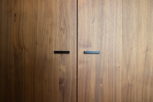 Beautiful brown wooden oak doors of a cabinet with black modern handles modern background texture close-up