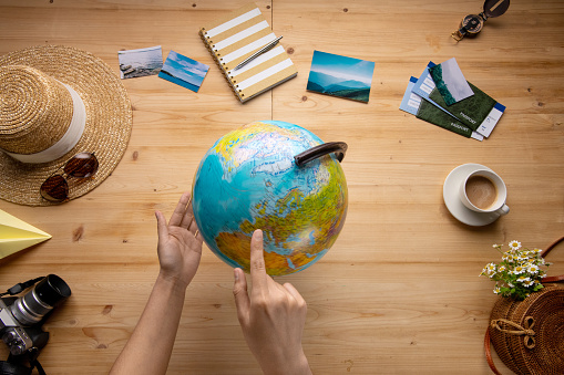 Above view of unrecognizable woman pointing at globe while choosing country for travel