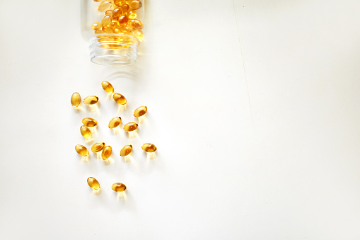 Shot of spilled fish oil pills from a bottle on white background