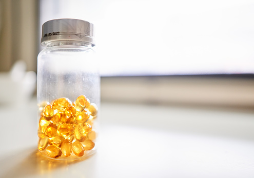 Shot of fish oil pills in a bottle on white table