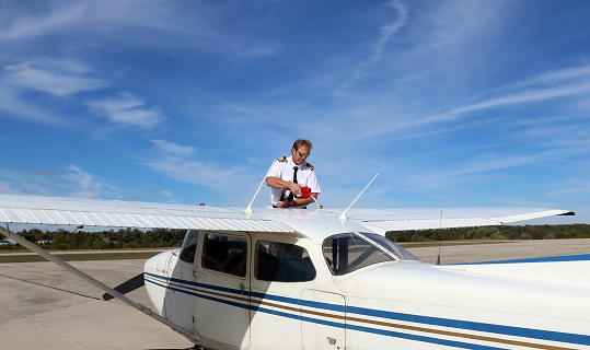 Flight instructor pilot filling the airplane with jet fuel with hair blowing in the wind with lots of copy space