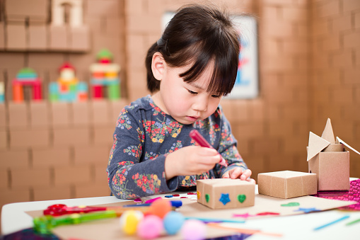 toddler girl  making craft by using cardboard for homeschooling