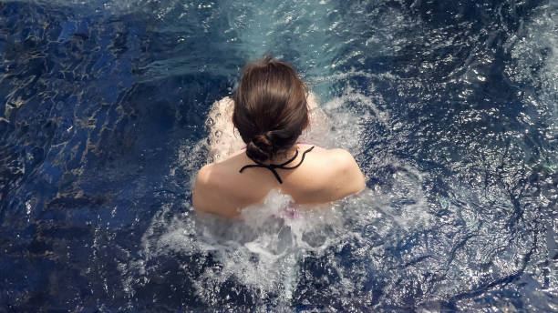 istock brunette sits in blue outdoor hydromassage pool water with white foam 1250105047