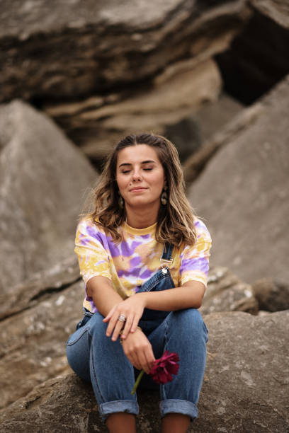 istock Young woman sitting on rocks 1250105934
