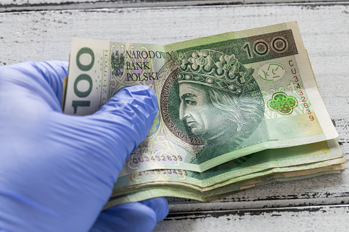 money from Poland, one hundred zlotys banknotes kept in rubber gloves. The concept of economy and financial threats during the Coronavirus pandemic