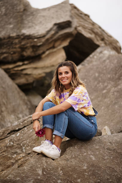 istock Young woman sitting on rocks 1250108216
