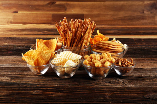 istock Salty snacks. Pretzels, chips, crackers in glass bowls on table 1250112243