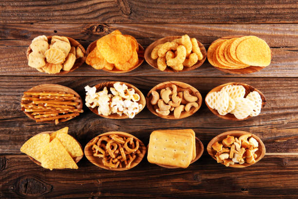istock Salty snacks. Pretzels, chips, crackers in wooden bowls on table 1250112699
