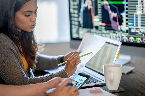 Concentrated businessman trader looking at pc monitor with diagram of stock crypto currency market, pointing with pen at screen, touching chin analyzing tendency of money flow, inventing new strategy