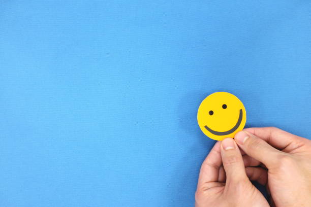 istock Hands holding a yellow smiley face in blue background with copy space. Positivity and happiness concept. 1250120041
